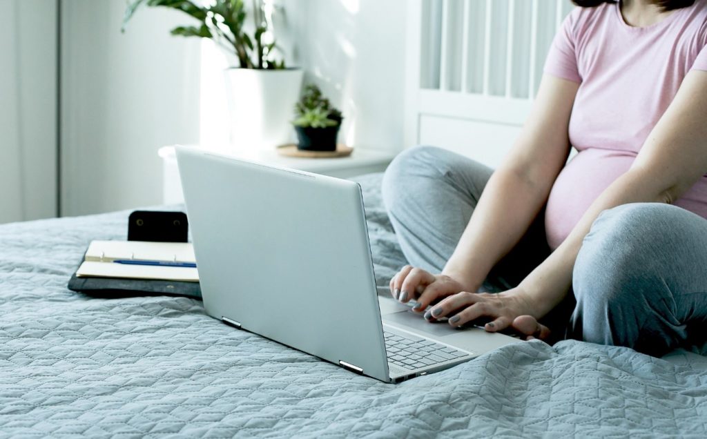 Mujer sentada en una cama con una laptop

Descripción generada automáticamente con confianza media